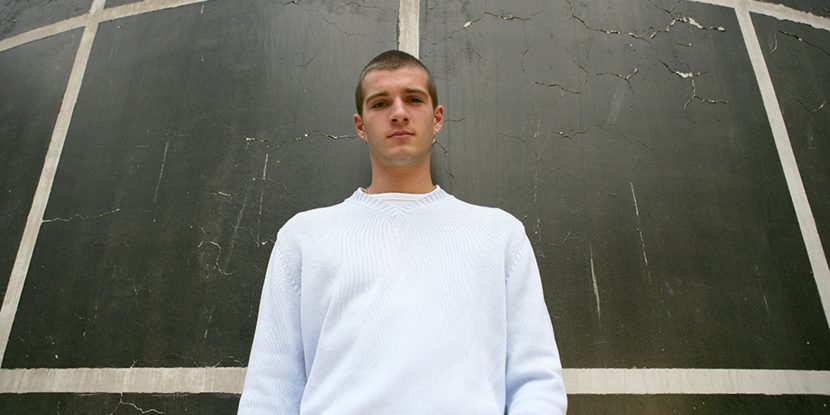 A young man standing against a wall